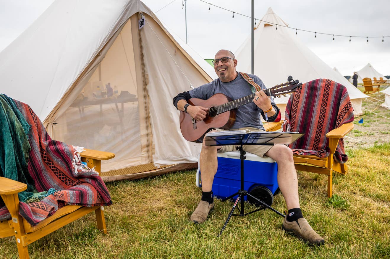 A man playing a guitar in The Gorge campground.