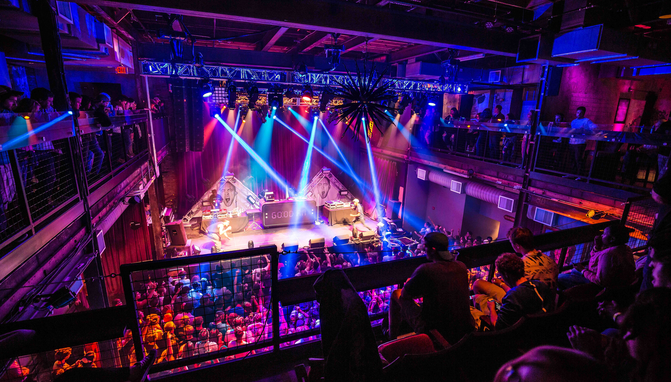 A DJ set lights up the stage as a packed crowd and balcony viewers enjoy the show at the Mercury Ballroom